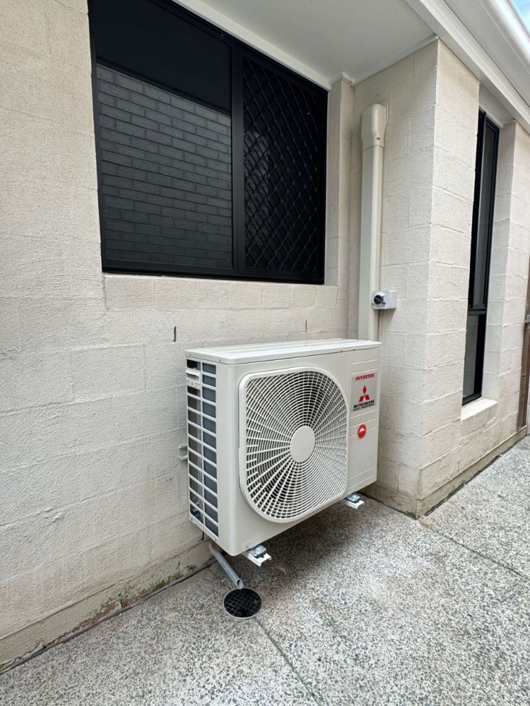 Split system outdoor unit on a stand beside a house