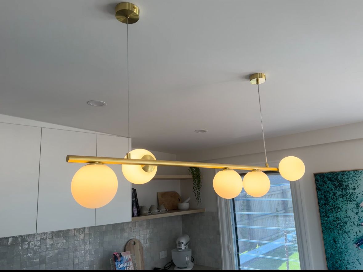Brass pendant light with glass globes over a kitchen bench