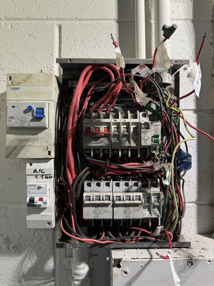 Old switchboard with crowded, messy wiring before an upgrade