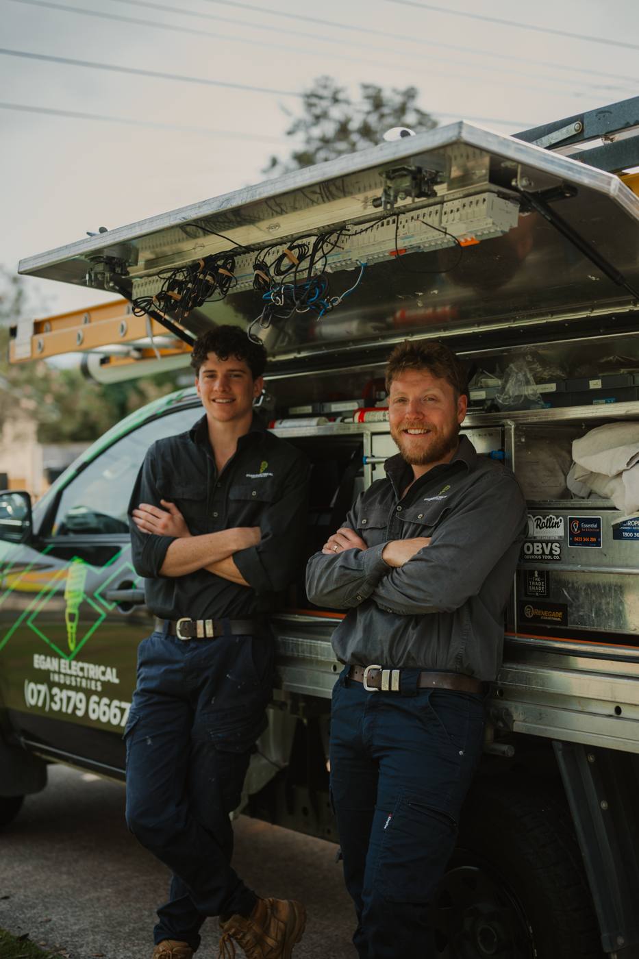Two Egan Electrical electricians standing beside the branded ute